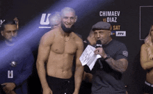 a shirtless man stands next to a man with a microphone and a sign that says chimaev vs diaz