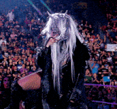 a woman with long white hair and horns stands in front of a crowd with a sign that says festival