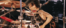 a man with a tattoo on his arm is playing drums in front of a drum set with the number 20 on it