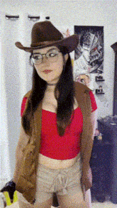 a woman wearing a cowboy hat and glasses is standing in a room .