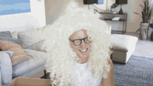a man wearing a white wig and glasses smiles