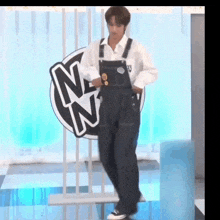 a man wearing overalls is standing in front of a sign that says nn