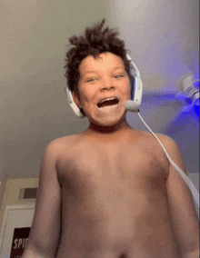 a shirtless boy wearing headphones and a microphone making a face