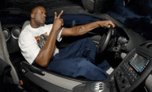 a man with a tattoo on his arm is sitting in the driver 's seat of a car