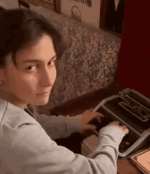 a woman is typing on a typewriter while sitting at a table .