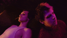 a man and woman are laying back to back in a dark room
