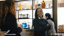 a woman stands with her arms crossed in front of a shelf that says nbc on it