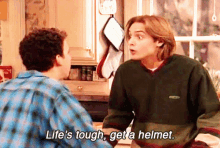 two men are talking in a kitchen and one of them is saying life 's tough get a helmet