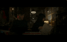 a man and a woman are sitting in a dark room reading a book