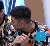 a man with a tattoo on his neck is wearing a colorful shirt and giving a thumbs up