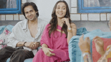 a man and a woman are sitting on a couch and smiling