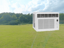 a white air conditioner is sitting in the middle of a field