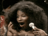 a woman with very long hair is singing into a microphone .