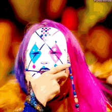 a woman with pink hair is wearing a clown mask and covering her face