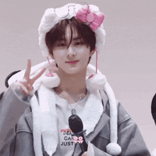 a young man wearing a hello kitty hat and glasses makes a peace sign