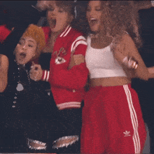 a group of women are dancing in a room with a man in a red jacket