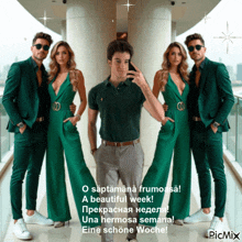 a man is taking a picture of himself surrounded by three women in green jumpsuits