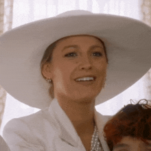 a woman wearing a white hat and white jacket smiles