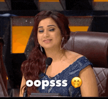 a woman sits in front of a microphone with the word oopsss written on her chest