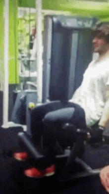 a man in a white shirt is doing leg exercises on a machine in a gym