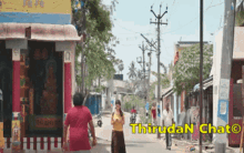 a woman walking down a street with a sign that says thirugan chat