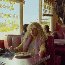 a woman sits at a table with a plate of food in front of a window that says ' beef '