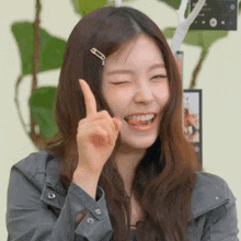 a woman with a hair clip on her head is smiling and giving a thumbs up sign