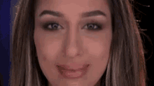 a close up of a woman 's face with long hair and a smile on her face .
