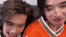two young men are sitting next to each other on a couch and smiling for the camera