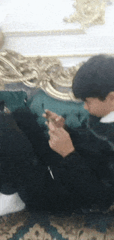 a young boy is sitting on a couch looking at his phone .