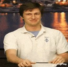 a man wearing a white shirt with the letter h on it is smiling