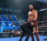 a man with a beard is standing in a wrestling ring carrying another man on his shoulders .
