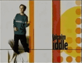 a man in a blue sweater is standing in front of a sign that says " talcolm iddle "