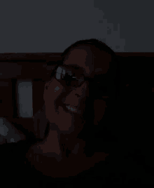 a woman wearing glasses and smiling in the dark