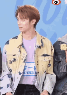 a young man wearing a purple shirt and a yellow jacket with chinese writing on it