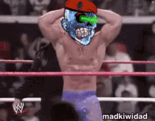 a wrestler with a skull on his head is in a ring with madkiwidad written on the bottom