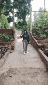 a woman is walking down a path in a park holding a cup .