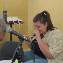 a woman singing into a shure microphone while wearing a shirt with the letter c on it