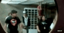 a group of people are standing in a room looking through a hole in a wall .