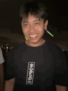 a man wearing a black shirt with chinese writing on it smiles