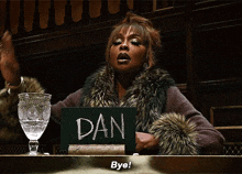 a woman in a fur coat is holding a sign that says dan bye
