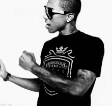 a black and white photo of a man wearing sunglasses and a t-shirt with a crown on it .