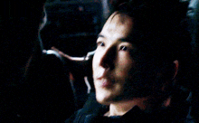 a close up of a man 's face in a dark room looking down .