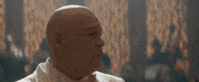 a bald man in a tuxedo and bow tie is laughing in a room .