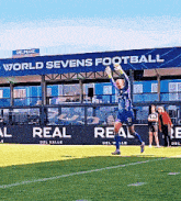 a soccer player is jumping in the air in front of a building that says world sevens football