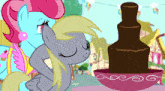 a couple of ponies standing next to each other with a chocolate fountain in the background