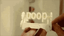 a person is holding a piece of paper with the word poop on it .