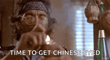 a man with glasses and a bandana on his head is smoking a cigarette .