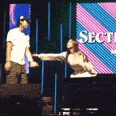 a man and a woman are dancing on a stage in front of a screen that says sect .