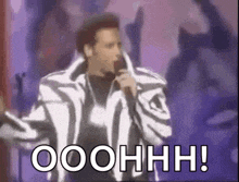 a man in a zebra print jacket is singing into a microphone with the words ooohhh written below him
